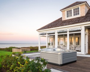 Jacuzzi Hot Tub installed on a deck outside of a modern home by the water.