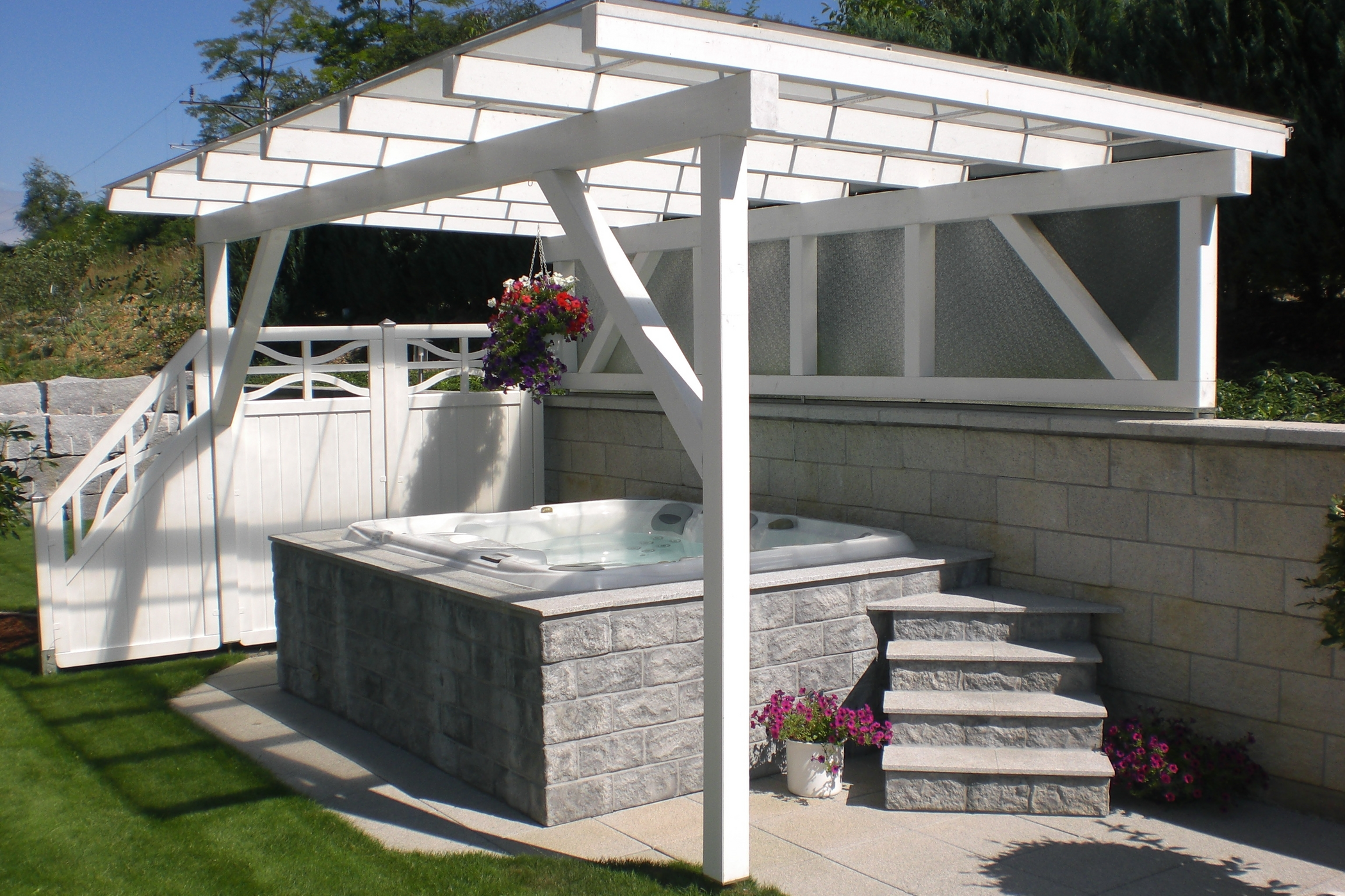 Outdoor hot tub installed underneath a white pergola.